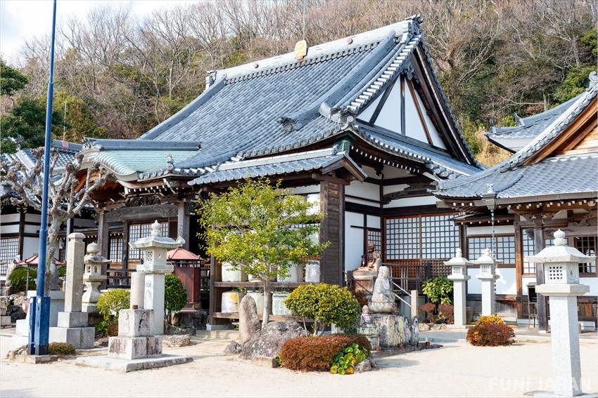A small traditional building with pointed roofs and immaculate landscaping.